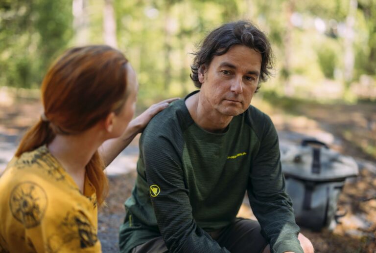 Kaksi henkilöä vierekkäin ja toinen lohduttaa koskettamalla kevyesti olkapäästä