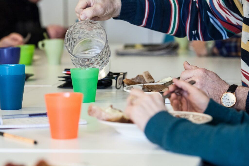 henkilö kaataa mukiin vettä, leivät lautasella