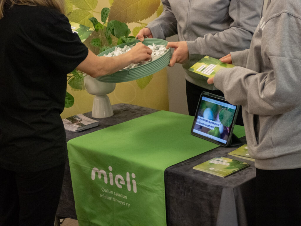 useampi henkilö tarjoaa kulhossa karkkia ihmiselle joka käyt mieli Oulun esittely pöydän äärellä