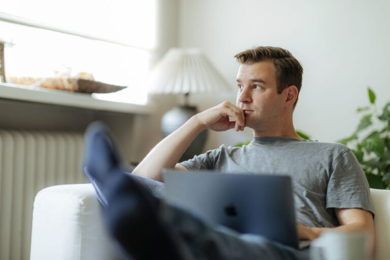 Henkilö istuu mietteliäänä tietokoneen äärellä.