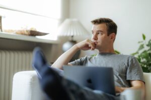 Henkilö istuu mietteliäänä tietokoneen äärellä.