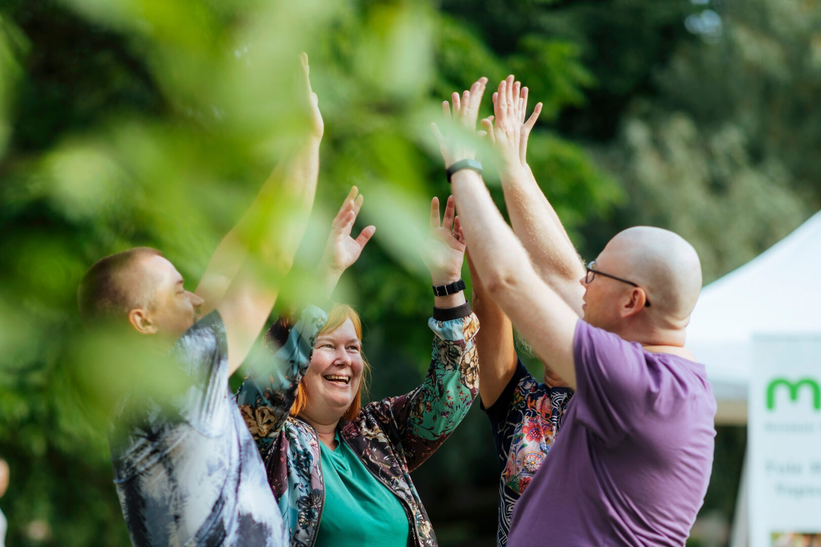 Pieni joukko iloisia ihmisiä kädet kohotettuina yhteen.