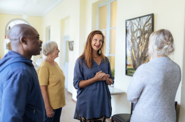 Ryhmä hymyileviä ihmisiä taidemaalauksen äärellä.