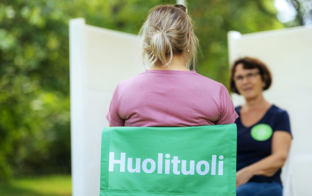 Henkilö istuu kasvokkain tukihenkilön kanssa Huolituolissa