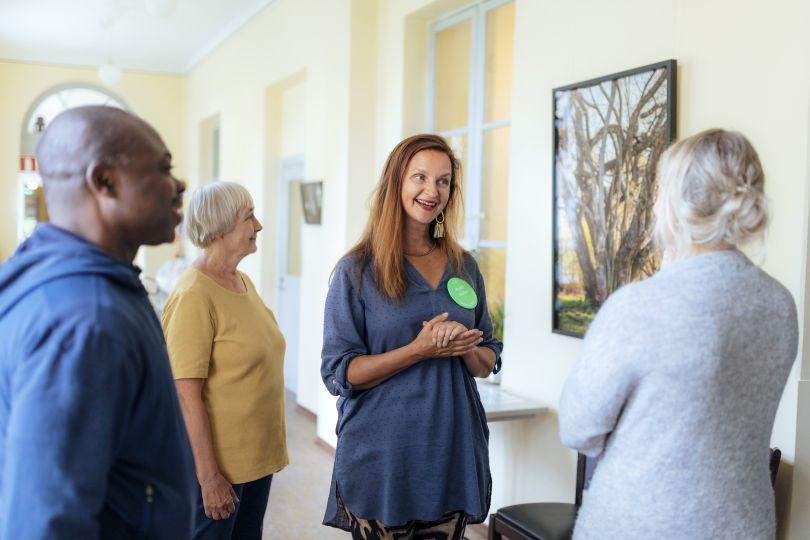 Vapaaehtoinen esittelee kolmelle muulle henkilölle taulua
