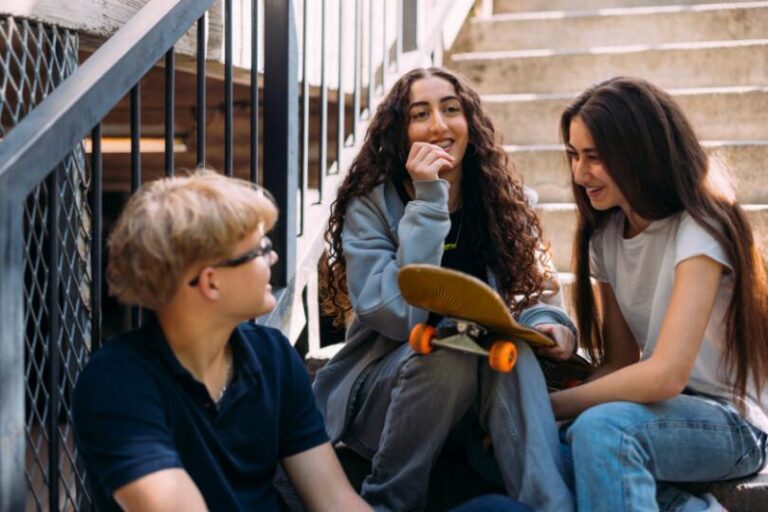 Kolme nuorta istuu portaikossa iloisena